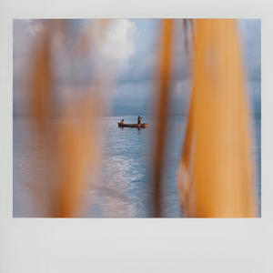 A small boat on a calm sea, seen through orange curtains